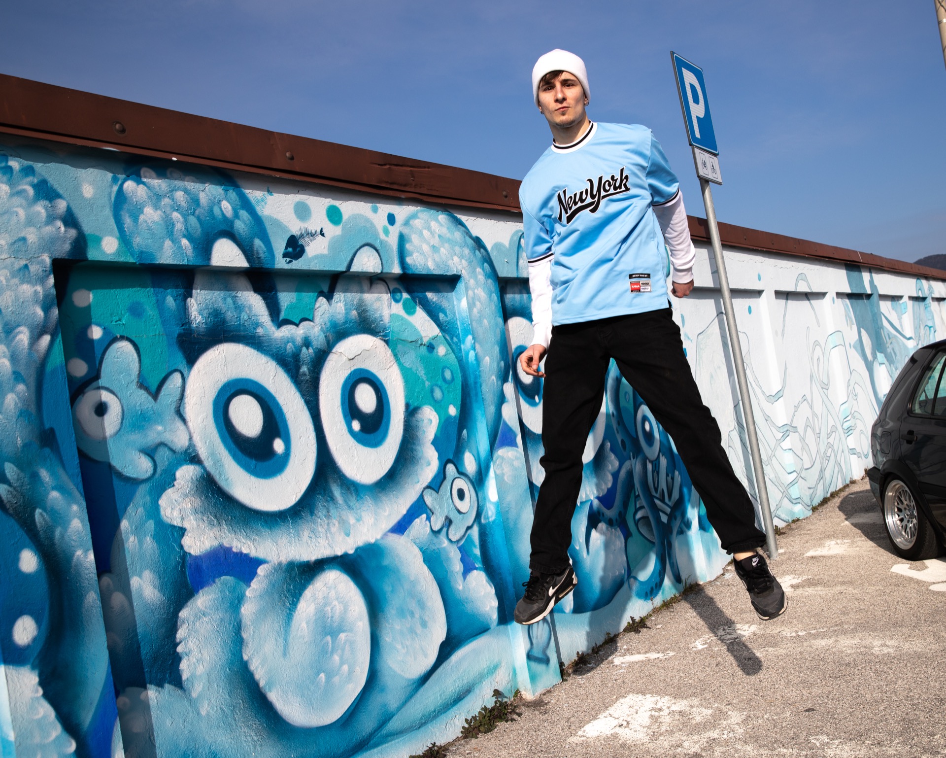 Young man jumping in front of a street art mural
