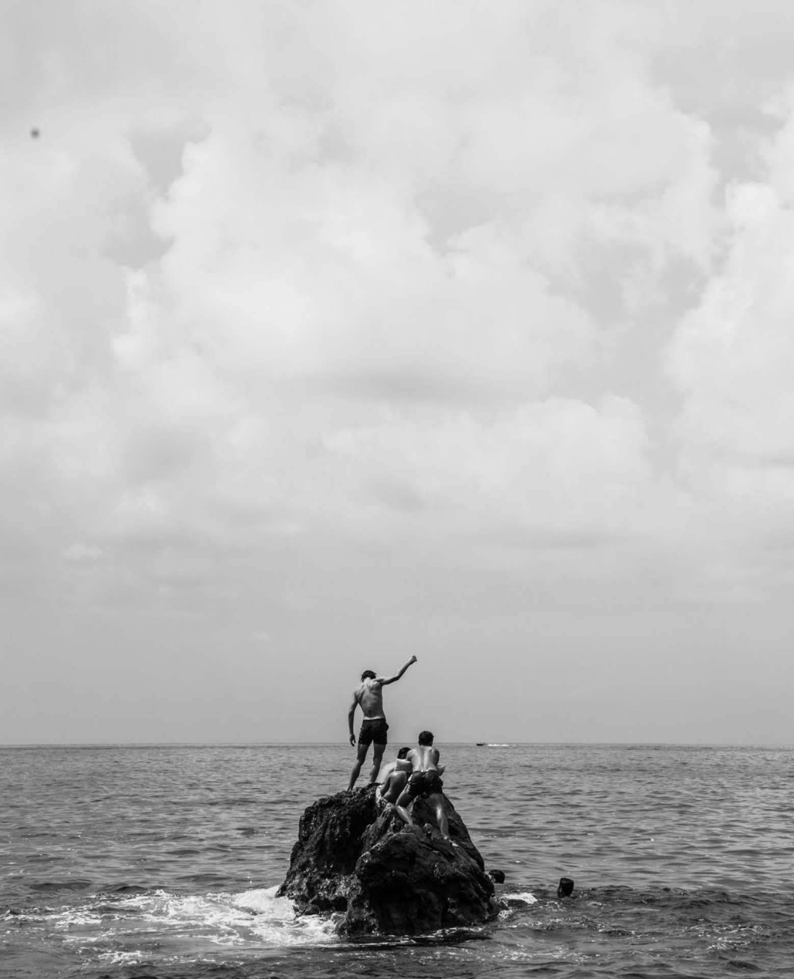 Boys standing on a sea rock, black and white, southern Italy