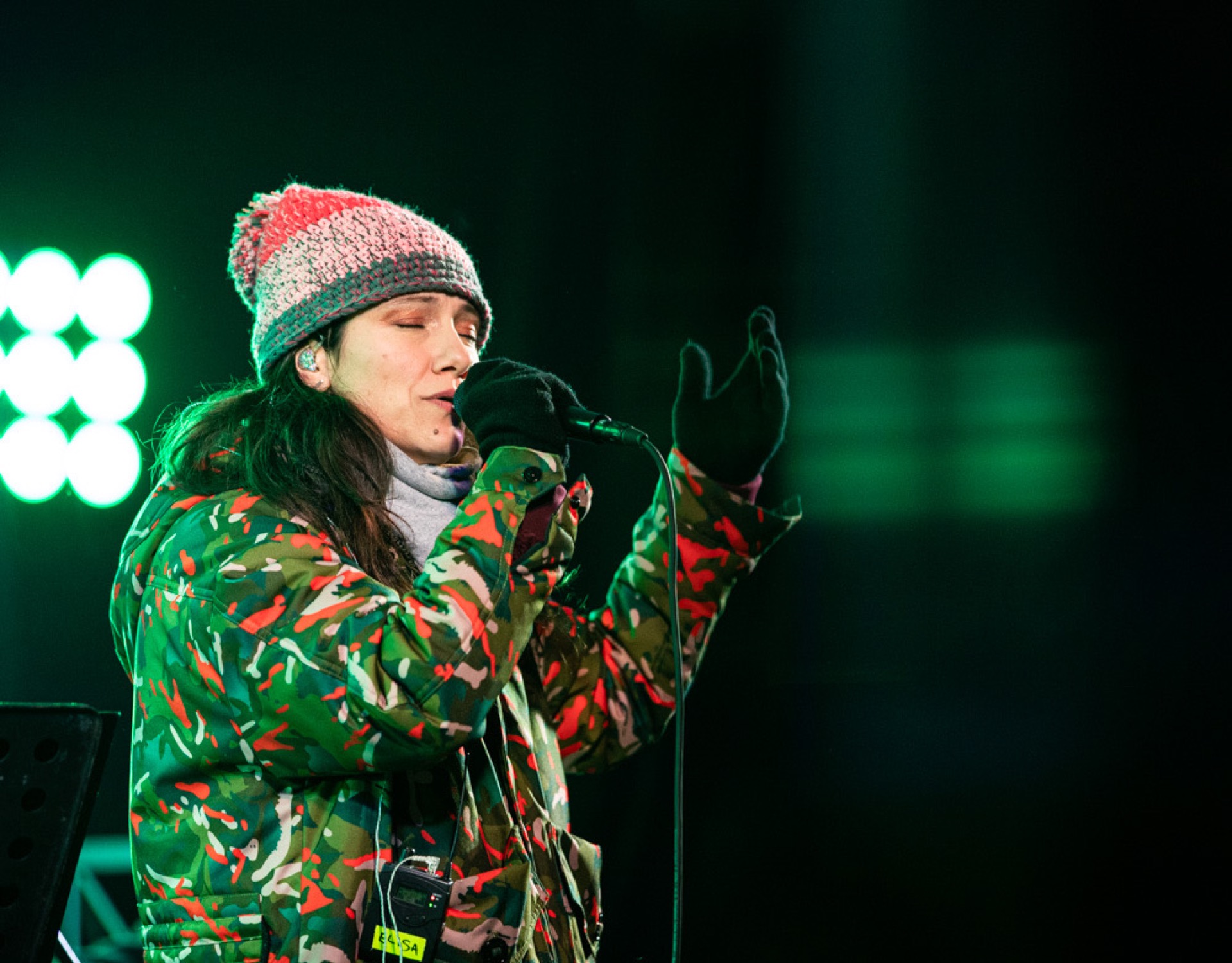 Singer Elisa performing outdoors with green stage lights