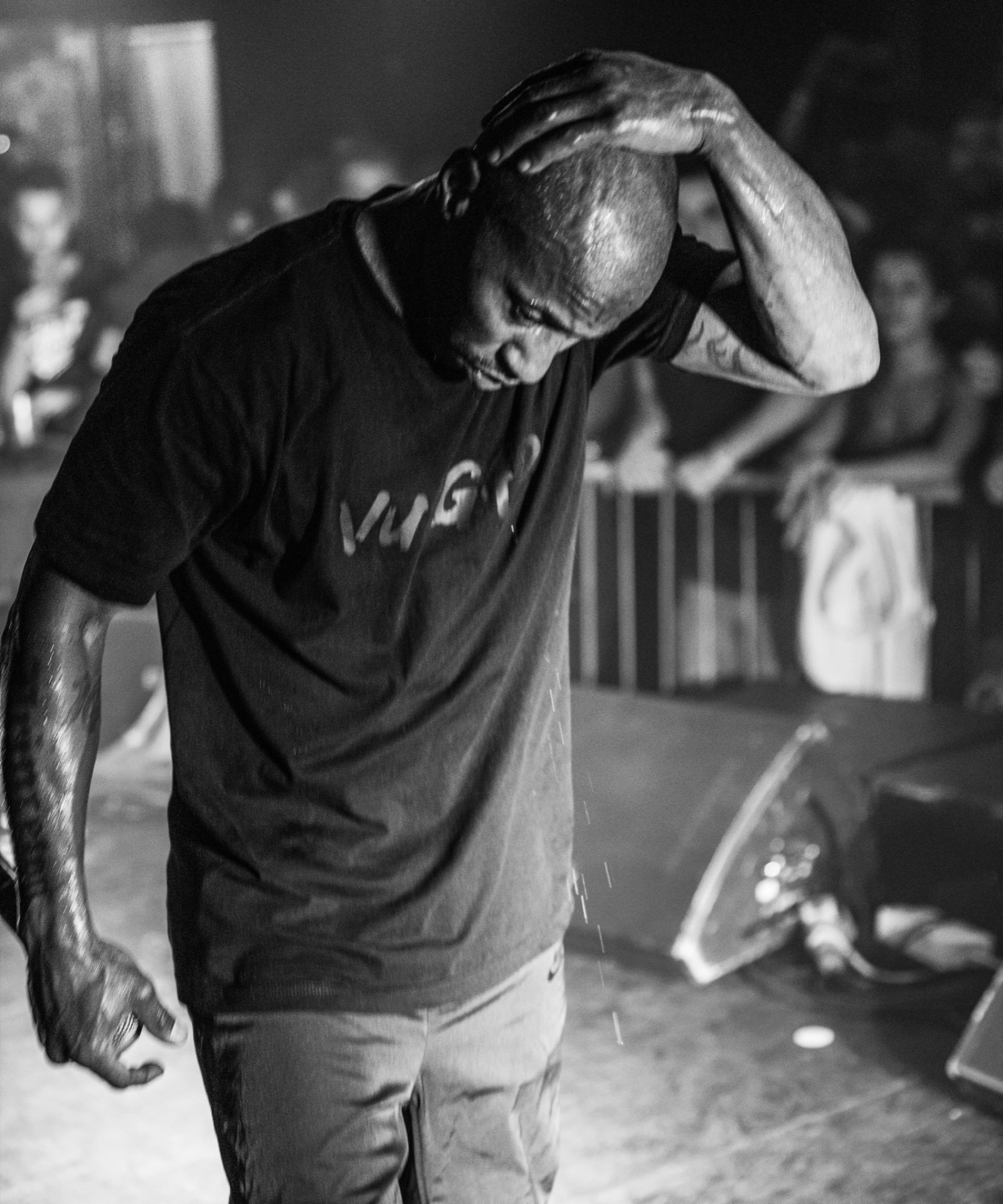 Hip hop performer bowing head on stage, black and white