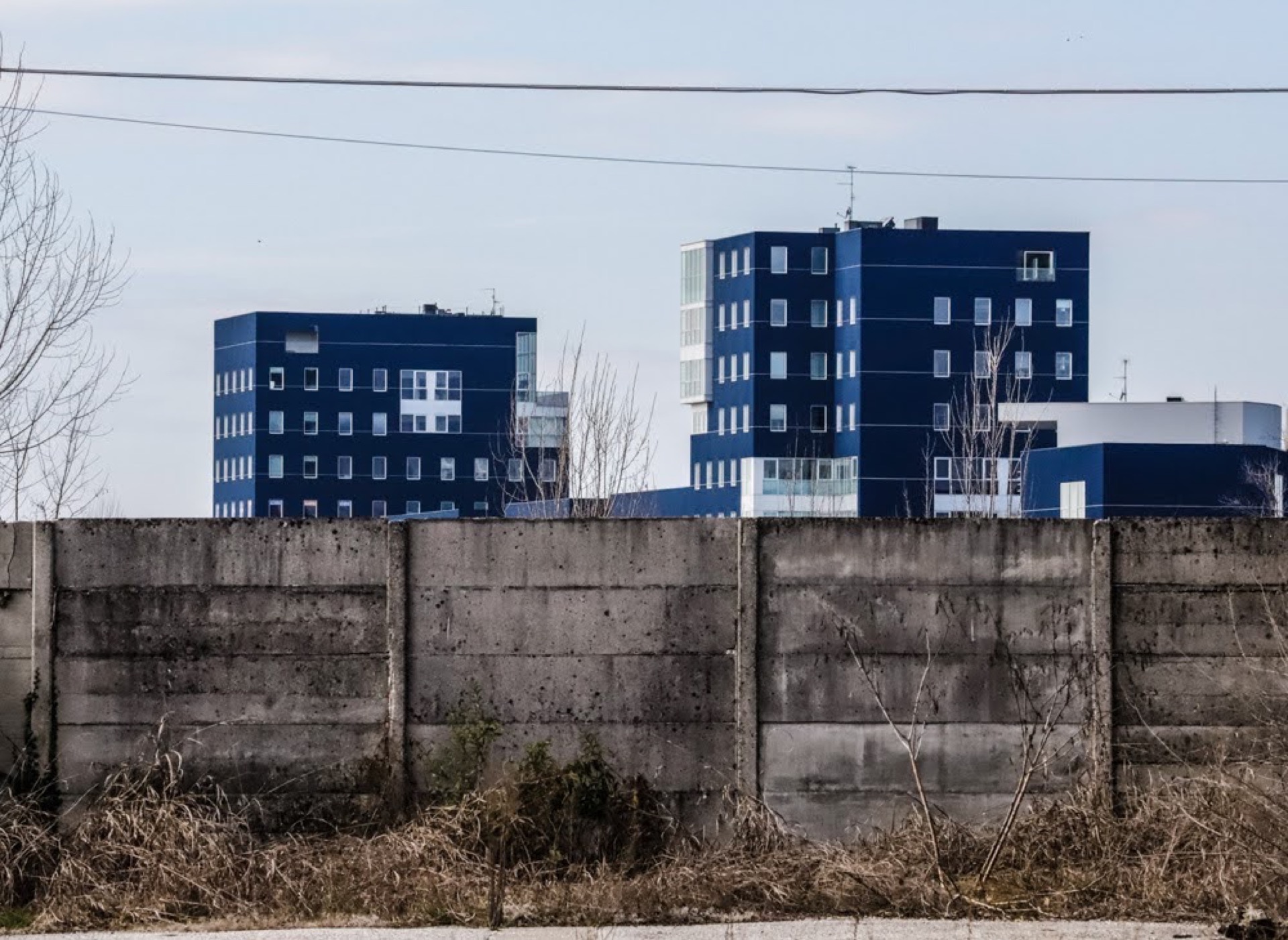 Blue residential buildings behind a concrete wall