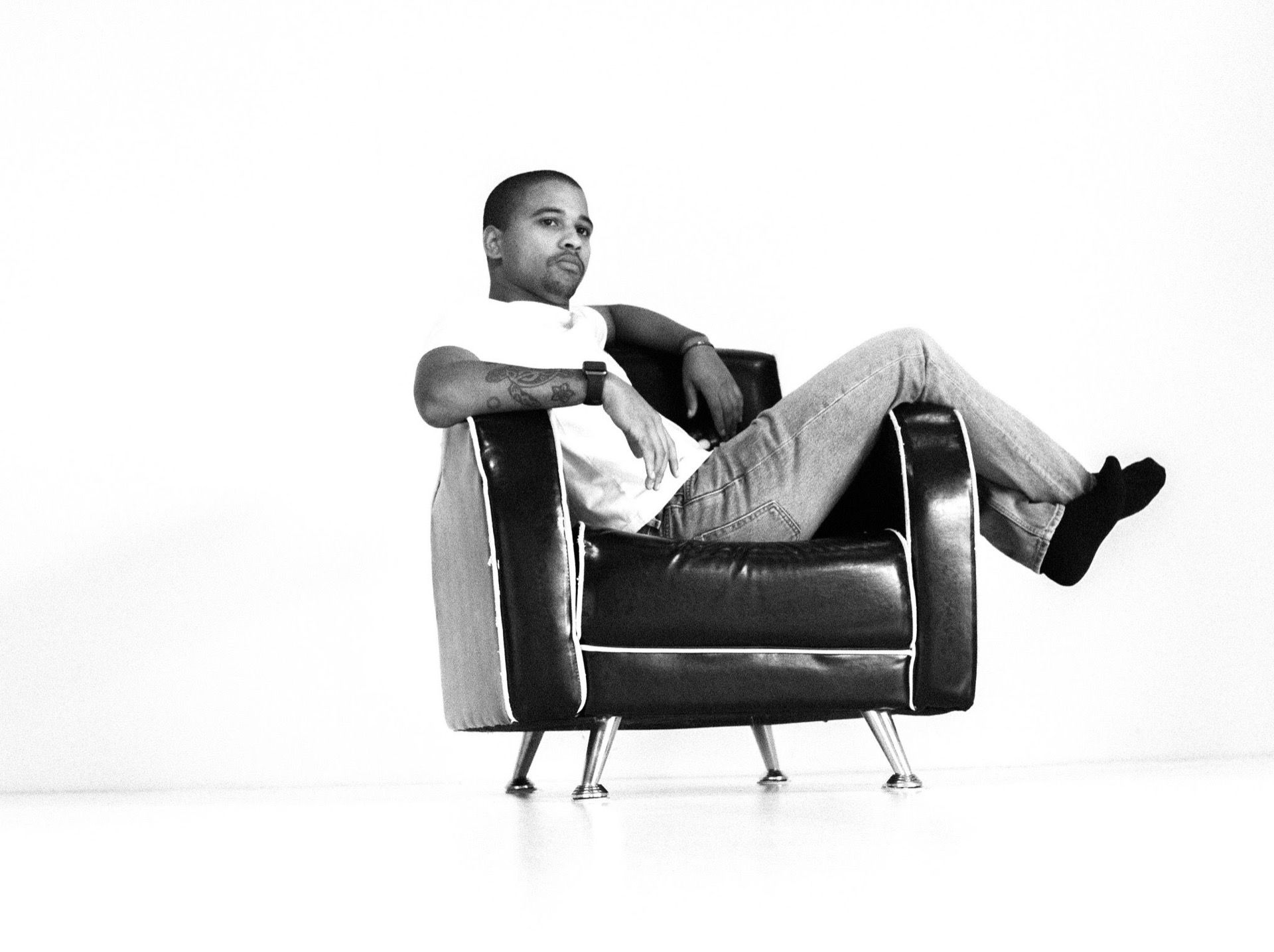 Man reclined in a leather armchair, black and white studio portrait