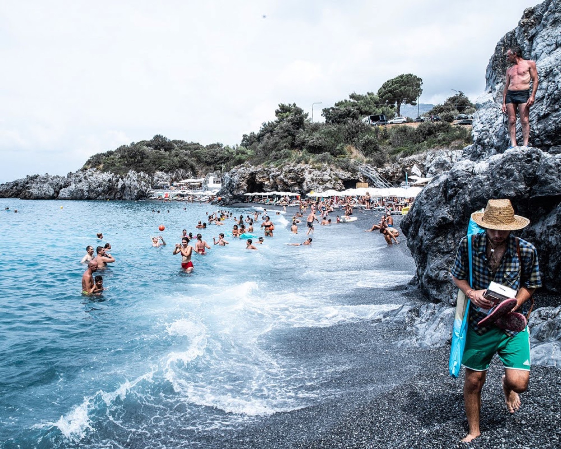 Rocky beach, man with straw hat and surfboard