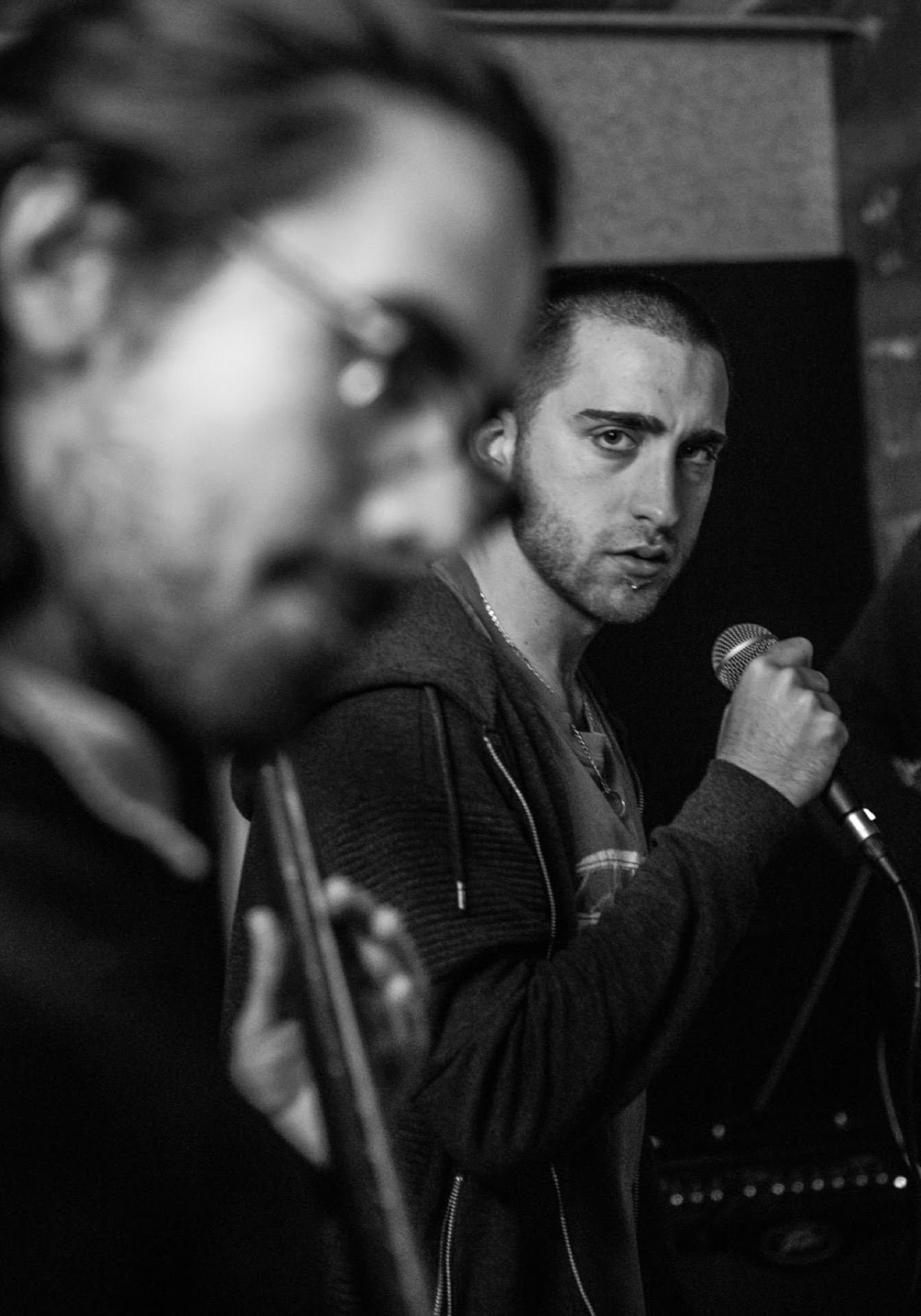 Singer at the microphone, blurred violinist in foreground, black and white